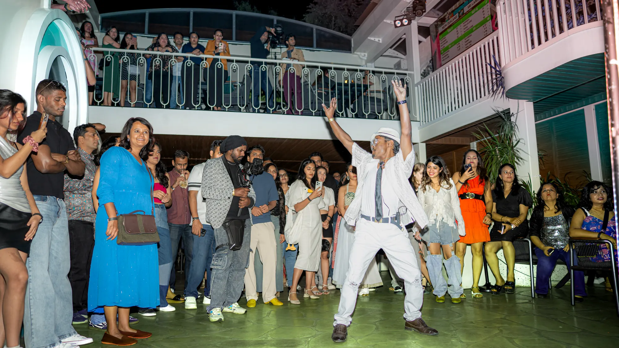 The courtyard at full tilt — a dancer leaping, the balcony packed