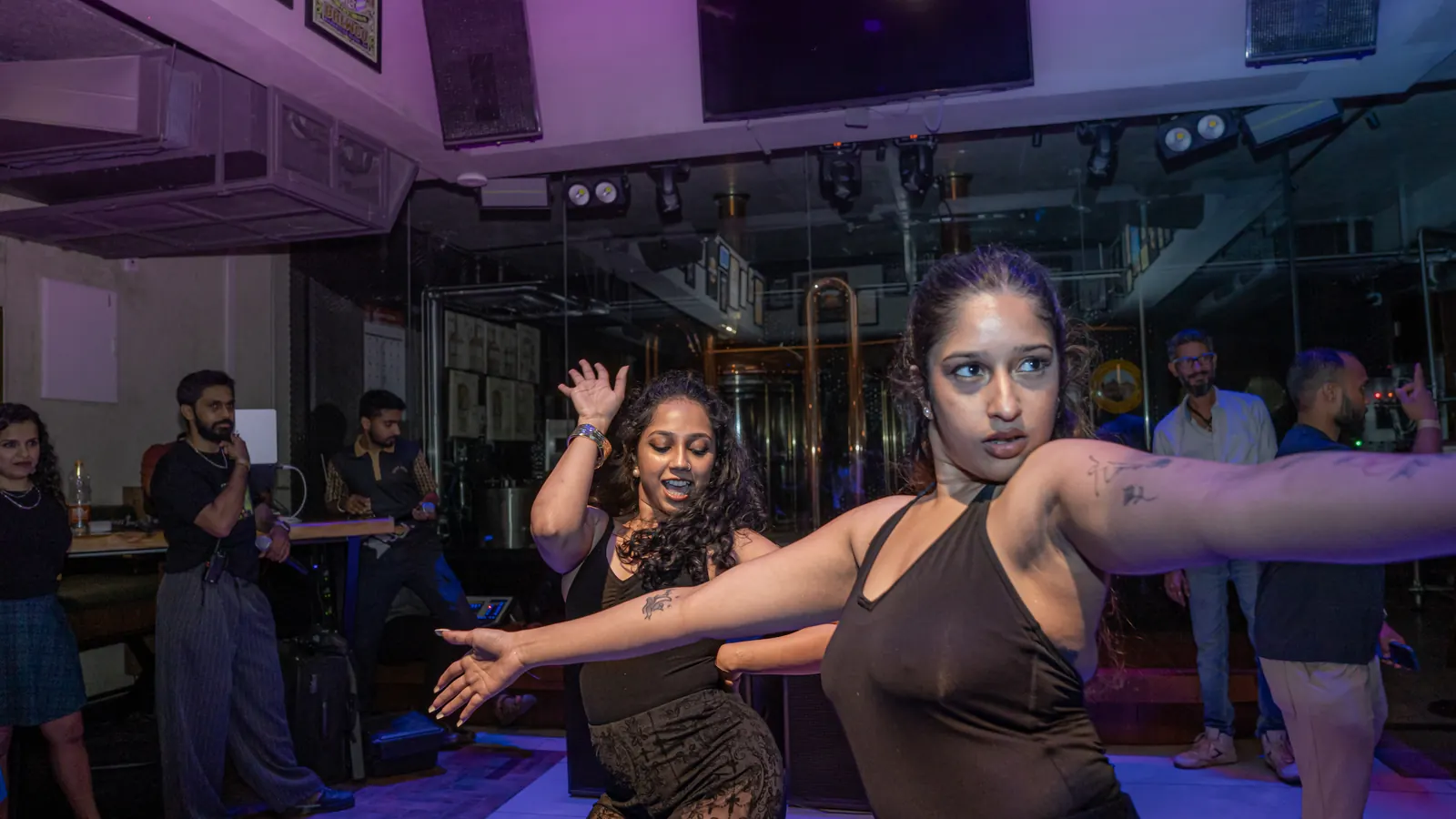 Two performers mid-move in blue light