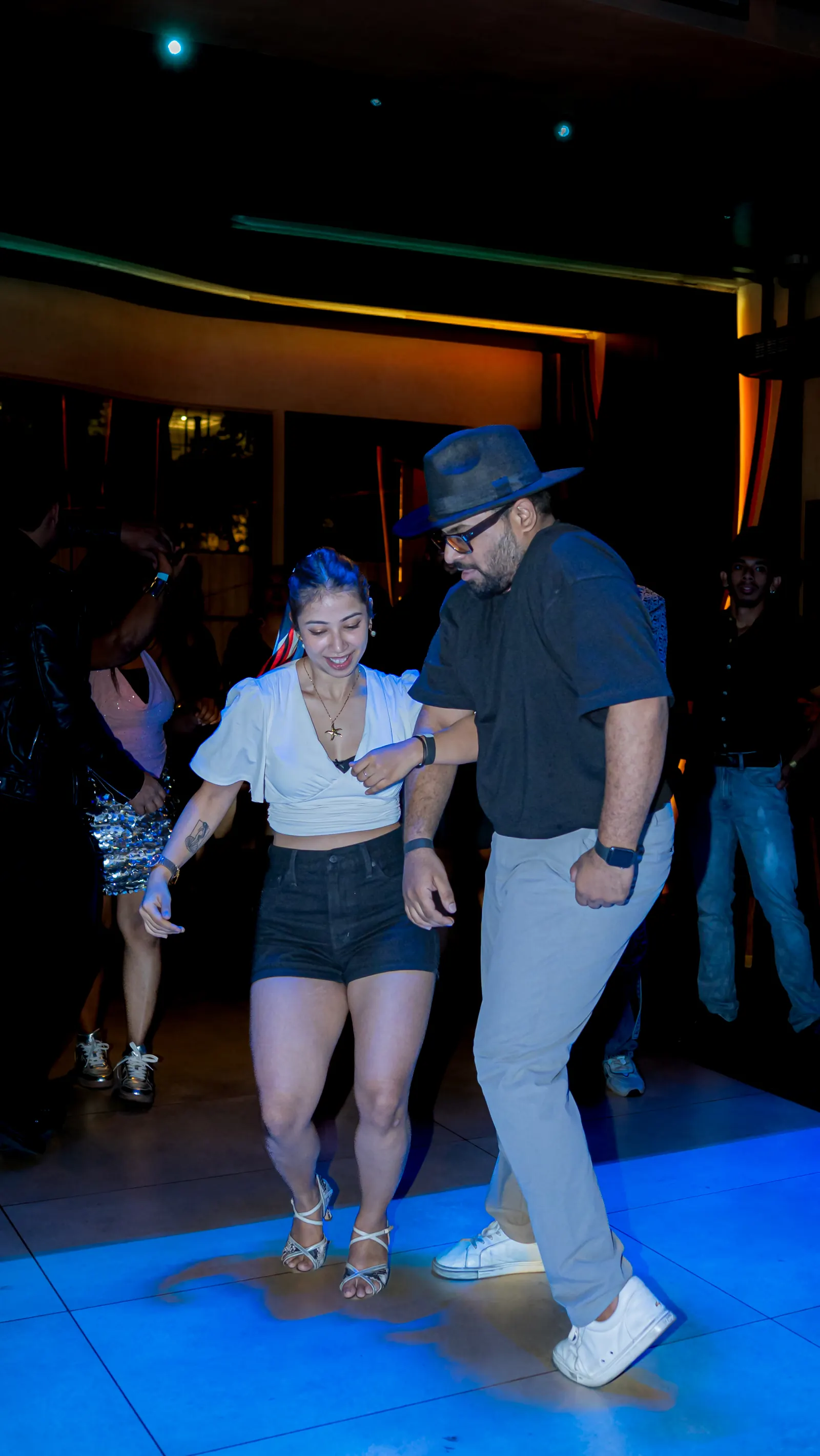 A couple mid-turn on the blue-lit floor